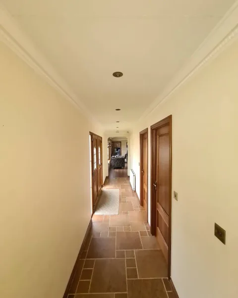 Cream hallway with white cornicing, wooden doors and tiled flooring