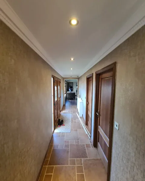 Hallway with textured gold walls, white ceiling and wooden doors