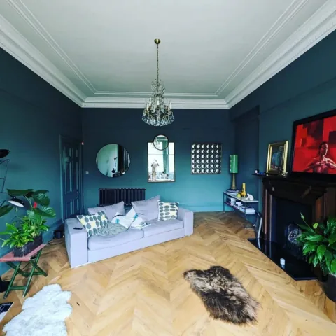 Teal sitting room with ornate white cornicing and herringbone flooring