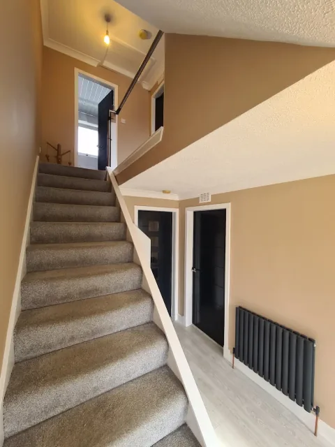 Neutral stairwell with white balustrade and dark radiator